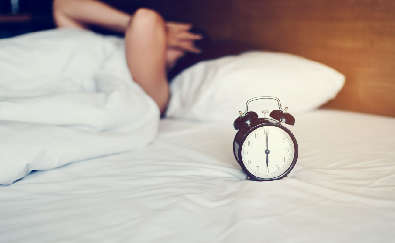 失眠可能是由於壓力過大或生活習慣不佳造成的。畫面中的鬧鐘顯示深夜時間，象徵著睡眠問題。解決方法包括保持規律的作息時間、減少咖啡因攝入、在睡前進行放鬆活動如閱讀或冥想，以幫助舒緩壓力和促進良好的睡眠品質。