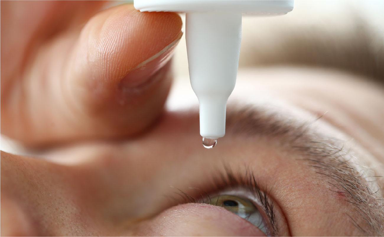 這張圖片顯示一個人在滴眼藥水，特寫鏡頭捕捉到一滴眼藥水即將進入眼睛。這強調了使用無防腐劑眼藥水的過程，並展示了其安全和溫和的應用。